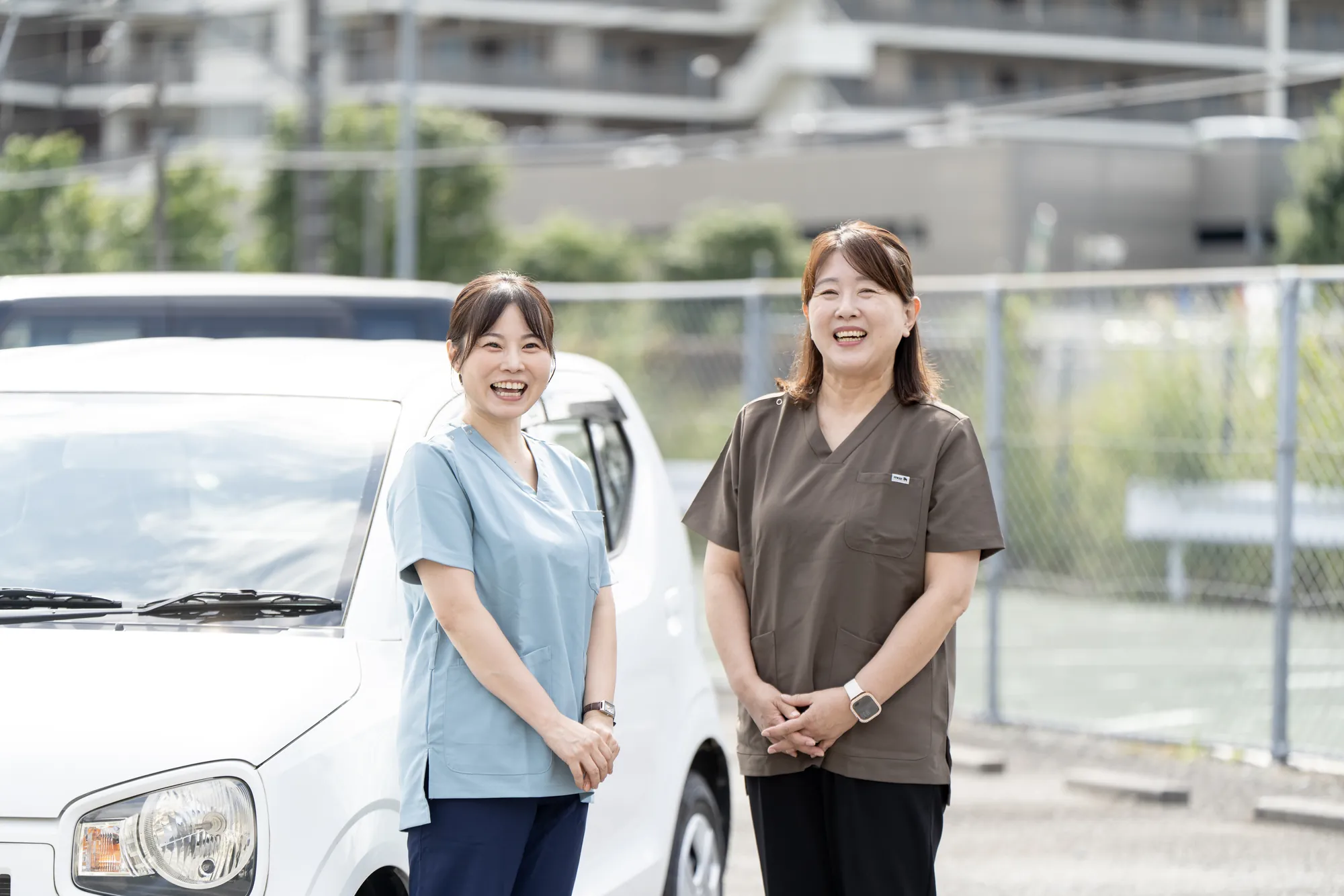 社用車の前で笑顔を見せる、陽和のスタッフ2名