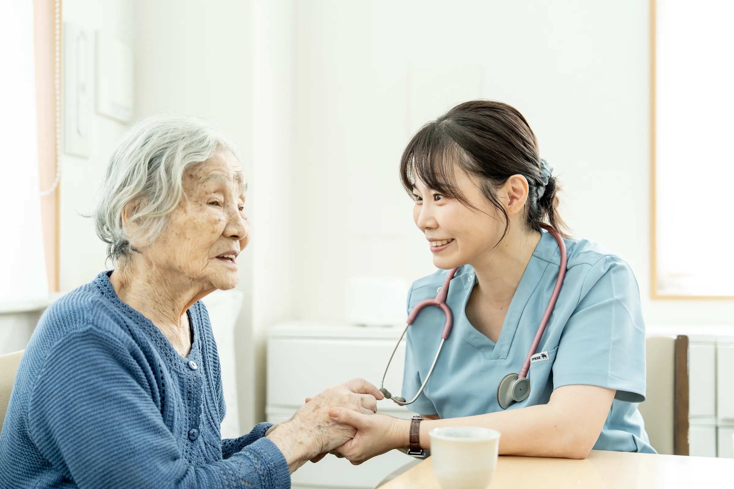 看護師が利用者さまの手を取り、笑顔で話している様子